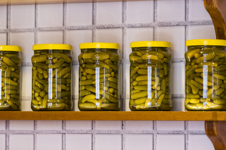 Glass jars with preserving vegetables on wooden shelves.の写真素材