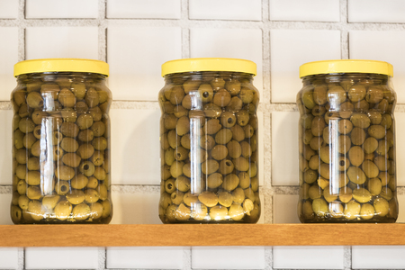 Glass jars with preserving vegetables on wooden shelves.の写真素材