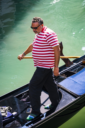 ITALY, VENICE - 5 SEPTEMBER, 2018: Men in gondoliers with tourists in Venice in Italy.のeditorial素材