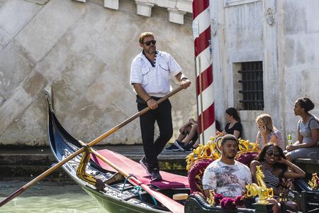ITALY, VENICE - 5 SEPTEMBER, 2018: Men in gondoliers with tourists in Venice in Italy.のeditorial素材
