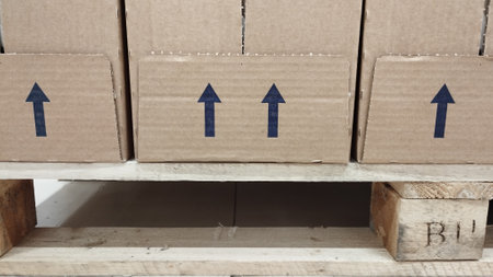 brown cardboard boxes for transportation and storage with blue up arrows painted on them, standing on a wooden standの写真素材