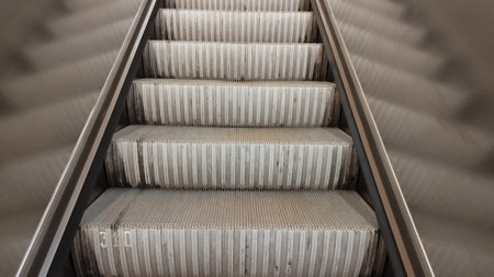 several empty escalator steps in the subway and their reflection on both sides in the side wall of the railingの写真素材