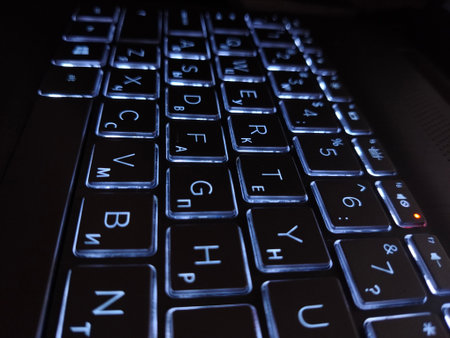 laptop keyboard in the dark, illuminated by blue lightの写真素材
