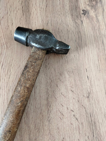 The hammer lies on a flat surface with a light wood texture.の写真素材