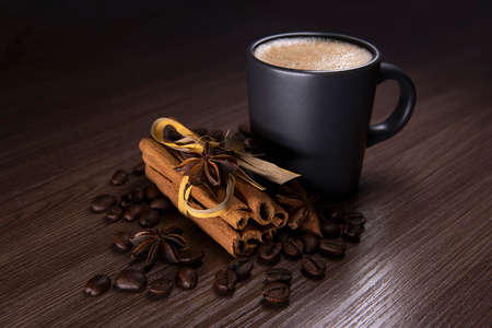 Cup of coffee, cinnamon sticks, star anise and coffee on a dark textured backgroundの写真素材