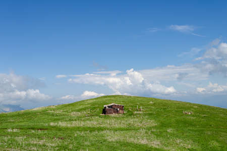 Little house on the hill. Blue sky with clouds, green grass. Place for textの写真素材