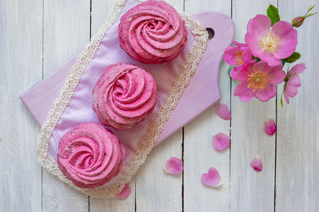 Homemade zephyr from currants on a white wooden background with pink flowers.の写真素材