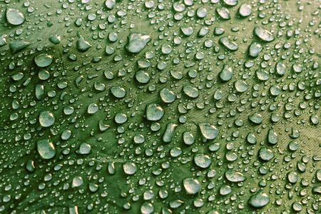 Rain water droplets on green color fiber waterproof fabric. Green background.の写真素材