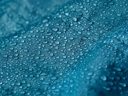 Rain water droplets on blue fiber waterproof fabric. Blue background.の写真素材