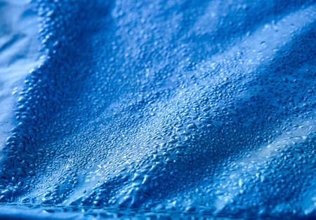 Water drops on waterproof membrane fabric. Detail view of texture of blue synthetic waterproof cloth. Morning dew on tent.の写真素材