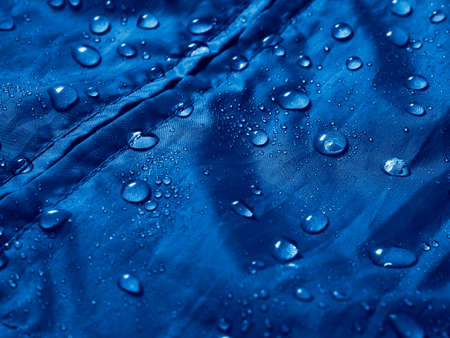 Water drops on waterproof membrane fabric. Detail view of texture of blue waterproof cloth.