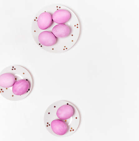 Colored eggs on plate with on white background. Flat lay. Copy space. Easter concept. Top view.