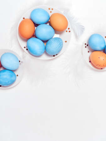 Colored eggs on plate with on white background. Flat lay. Copy space. Easter concept. Top view.の写真素材
