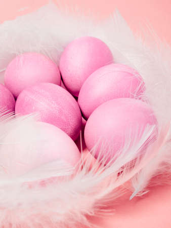 Easter eggs and feathers on pink background. Happy Easter concept.の写真素材