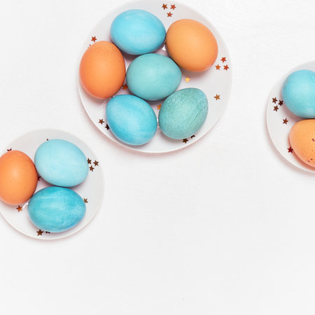 Colored eggs on plate with on white background. Flat lay. Copy space. Easter concept. Top view.の写真素材