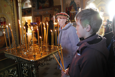 The boy in the Orthodox Church lights the candles on the altar in Russian on Palm Sundayのeditorial素材