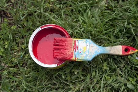 paint brush and pot of red paint on the green grassの写真素材