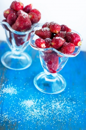 juicy strawberry with sugar in the glass beaker on the blueの写真素材