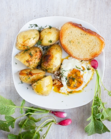rural breakfast - fried eggs, new potatoes, radish, breadの写真素材