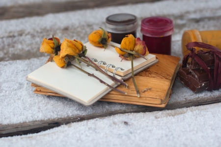 notebook, dry rose, paint and chocolate on the snow boardの写真素材