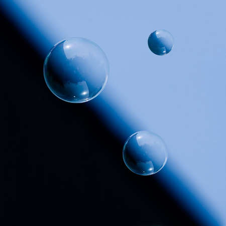 Three soap bubbles floating in the air, against a sky backgroundの写真素材