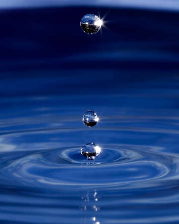 Three water spheres above a wave pattern created by dripping waterの写真素材