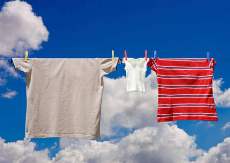 Three pieces of clothing of various size including  on a line drying in the sun