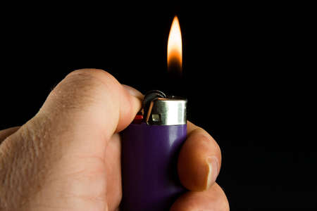 Lit cigarette lighter on dark backgroundの写真素材