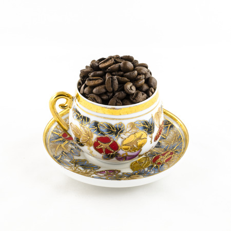 Porcelain coffee cup filled with coffee beans isolated on whiteの写真素材