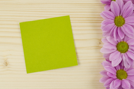 Blank green card and pink flowers on wooden backgroundの写真素材