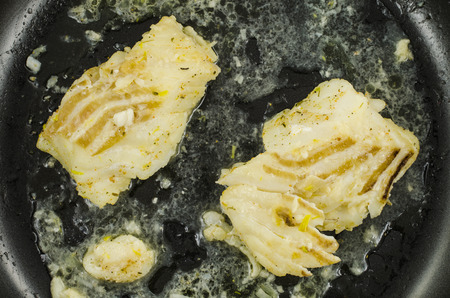 White cod on black frying panの写真素材