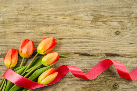 Empty wooden background with colorful flowers and red ribbonの写真素材