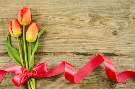Empty wooden background with colorful flowers and red ribbonの写真素材