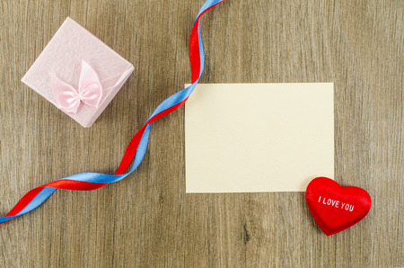 Empty card with heart and gift box on wooden backgroundの写真素材