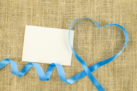 Empty card with heart shaped ribbon on linen backgroundの写真素材