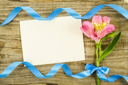 Colorful flower with ribbon and empty card on wooden tableの写真素材
