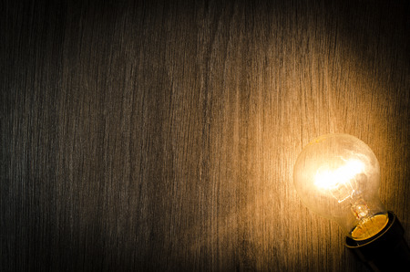 Glowing light bulb on wooden backgroundの写真素材