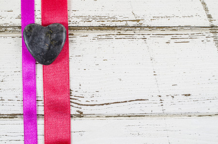 Heart shaped stone with ribbon on wooden tableの写真素材