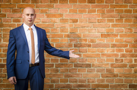 Young fashionable men in a suit against brick wallの写真素材