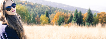 Young woman against autumn landscape backgroundの写真素材