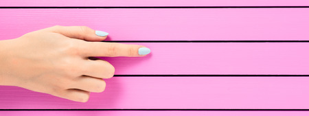 Female hand pointing on pink background