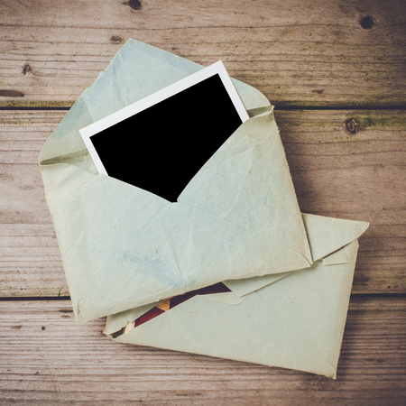 Old envelope with empty photo on wooden tableの写真素材