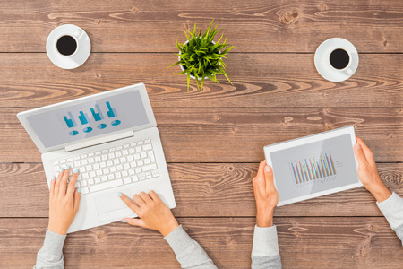 Man and woman working on computer and tablet in officeの写真素材