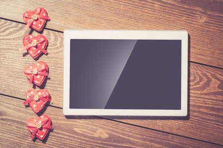 Red hearts and white digital tablet with blank screen on an old wooden tableの写真素材
