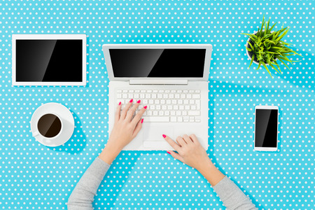 Woman using modern laptop over blue dotted tableの写真素材