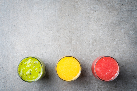 Glasses of fresh juice on gray stone tableの写真素材