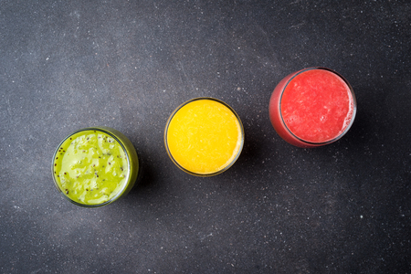 Glasses of juice on dark stone table. Top viewの写真素材