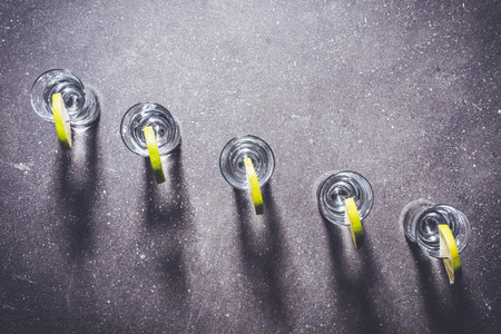 Shot glasses of vodka on dark stone tableの写真素材