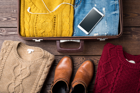 Open suitcase with female casual winter clothes on wooden table. Top viewの写真素材