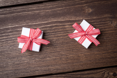 White gift boxes with red ribbon on wooden table. Top viewの写真素材